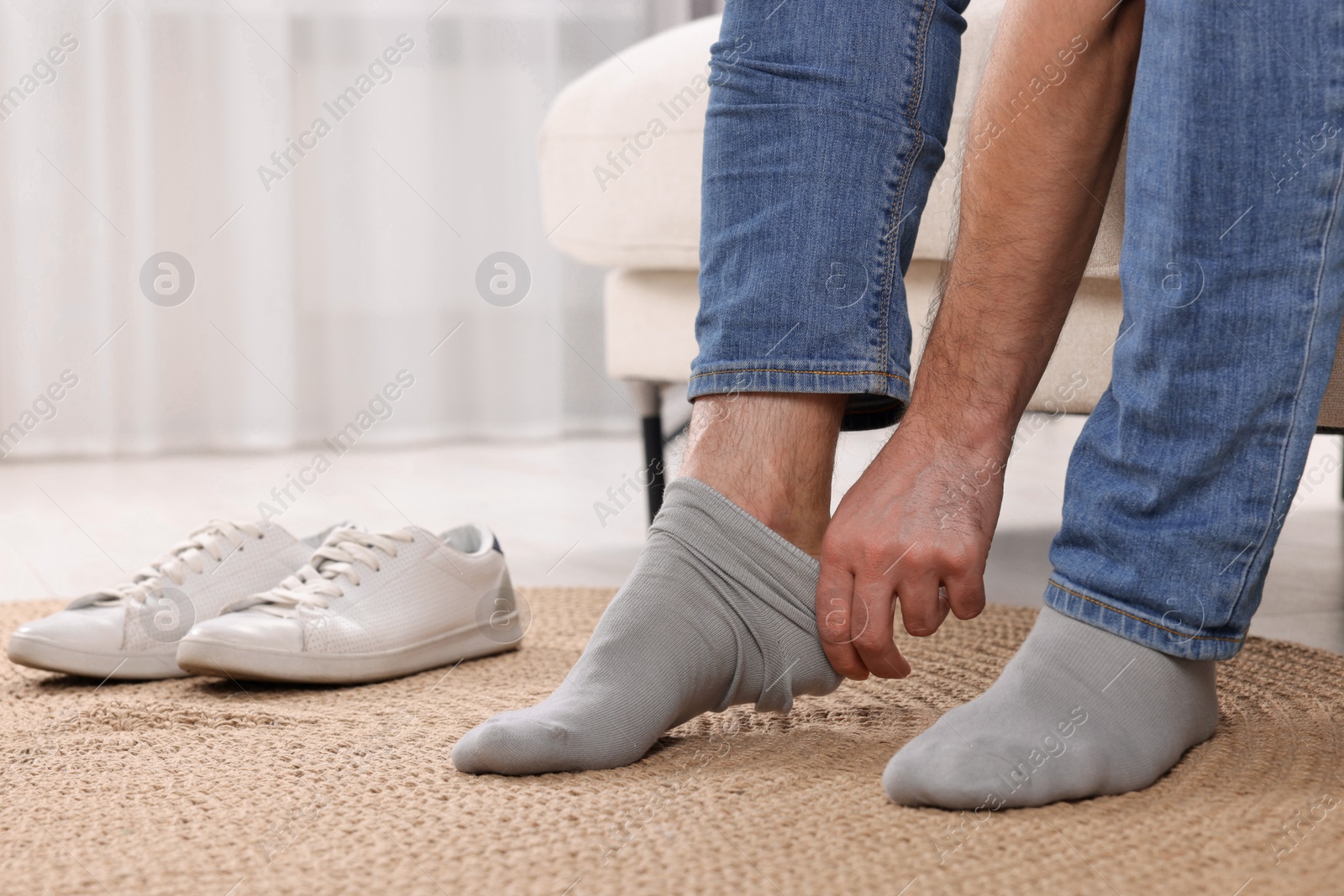 Photo of Man putting on grey socks at home, closeup