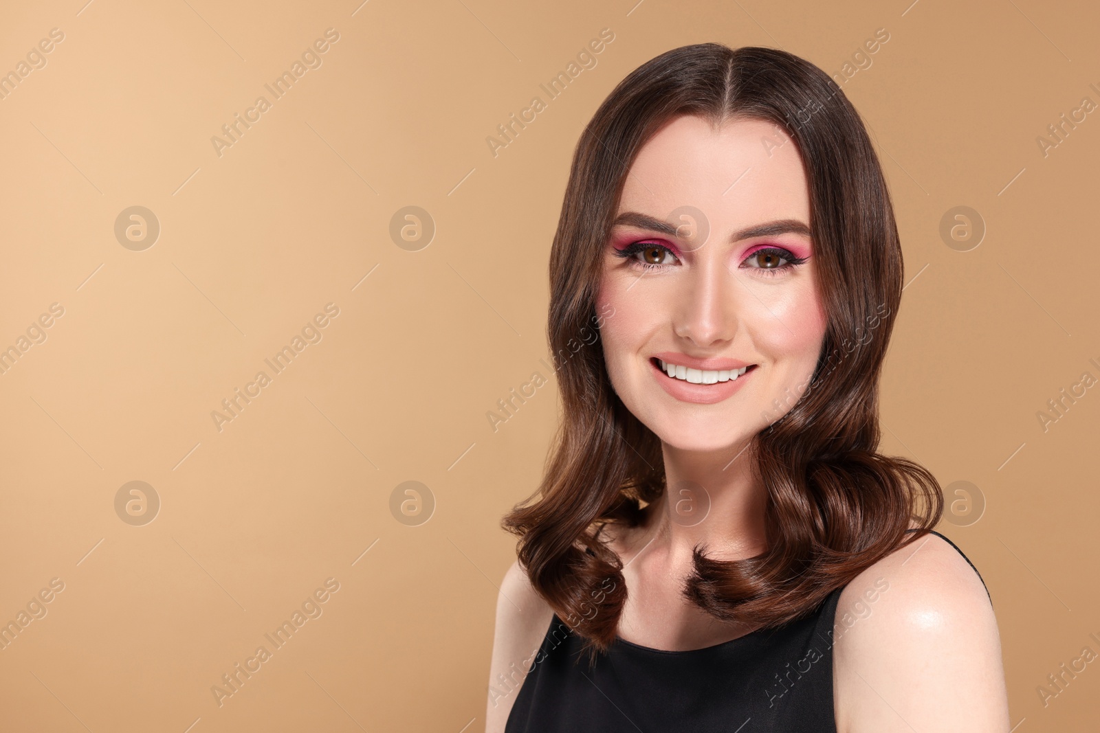 Photo of Portrait of beautiful young woman with makeup and gorgeous hair styling on beige background. Space for text