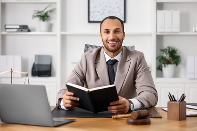 Photo of Smiling lawyer with book at table in office