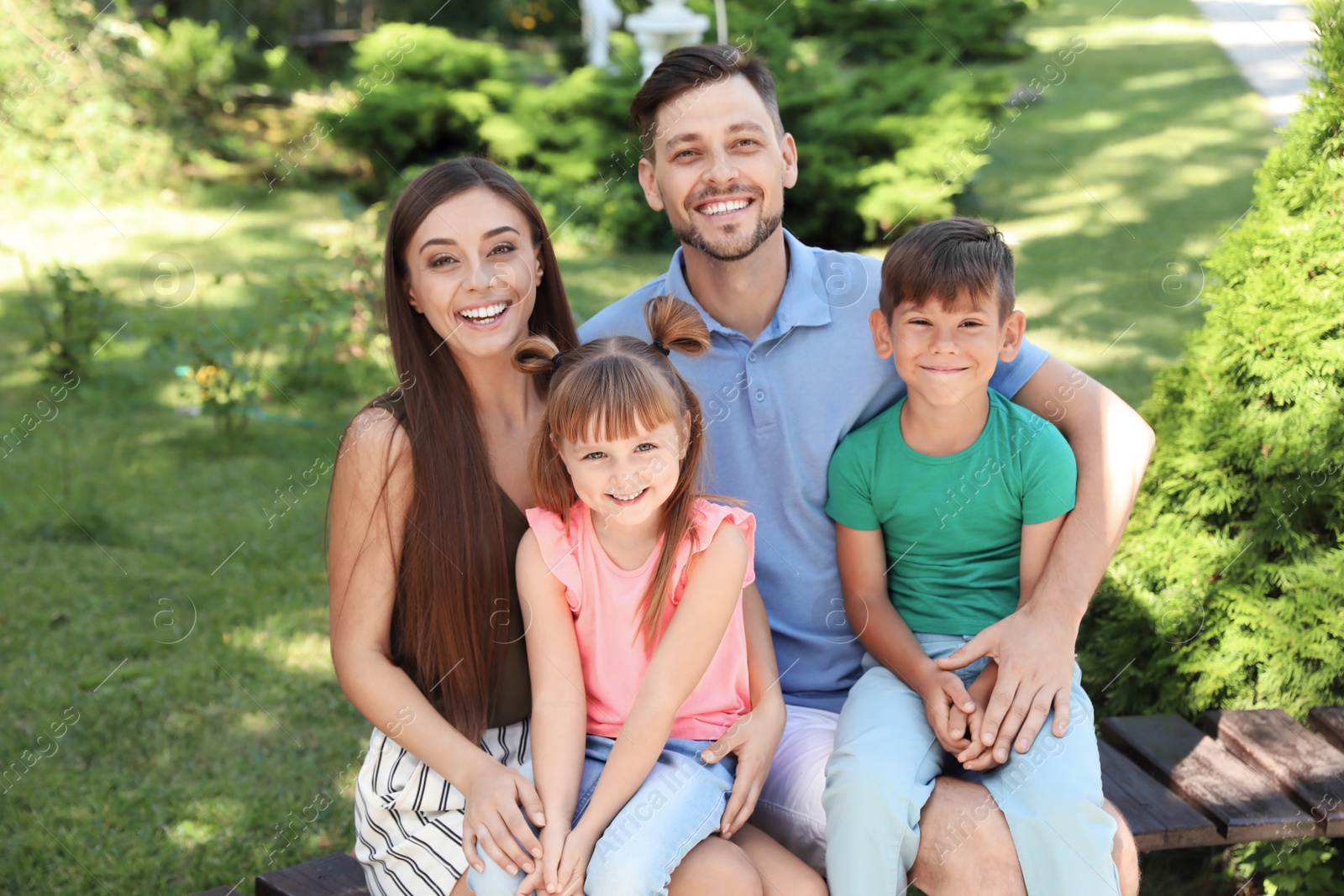 Photo of Happy family with children together on bench in park