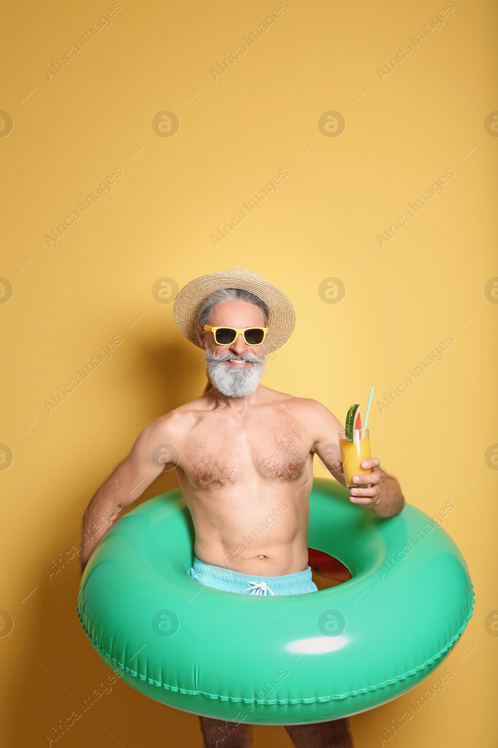 Photo of Shirtless man with inflatable ring and glass of cocktail on color background