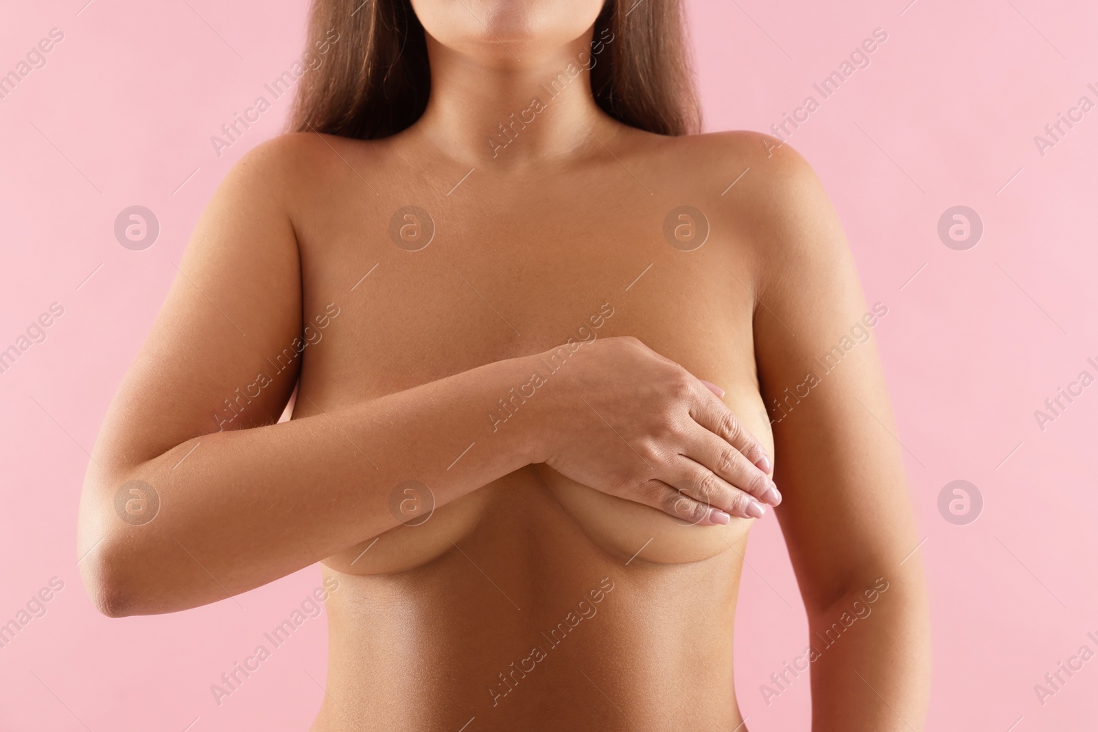 Photo of Naked woman covering her breast on pink background, closeup