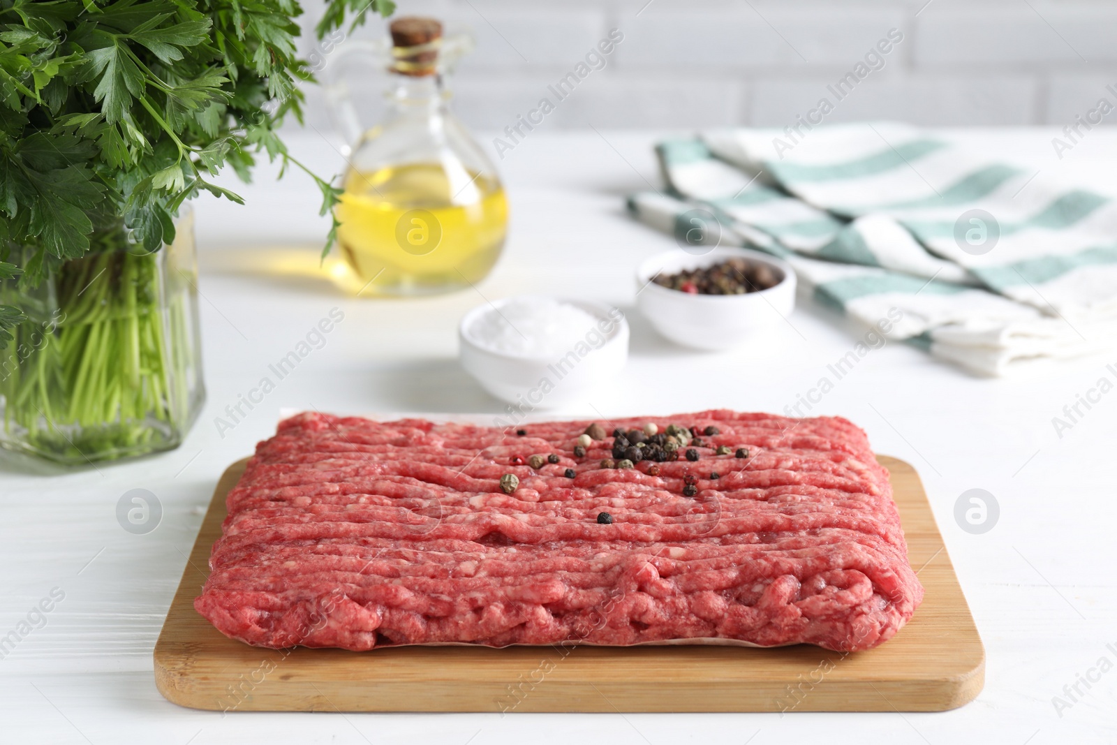 Photo of Raw ground meat, spices, oil and parsley on white wooden table