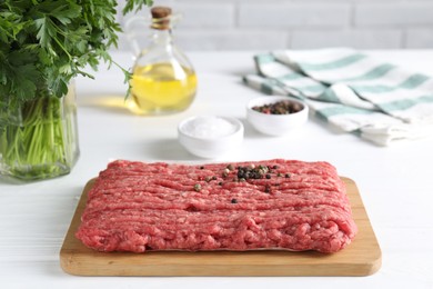 Raw ground meat, spices, oil and parsley on white wooden table