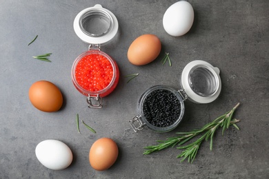 Photo of Glass jars with black and red caviar on grey background