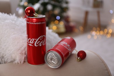 MYKOLAIV, UKRAINE - JANUARY 13, 2021: Cans of Coca-Cola and red Christmas balls indoors