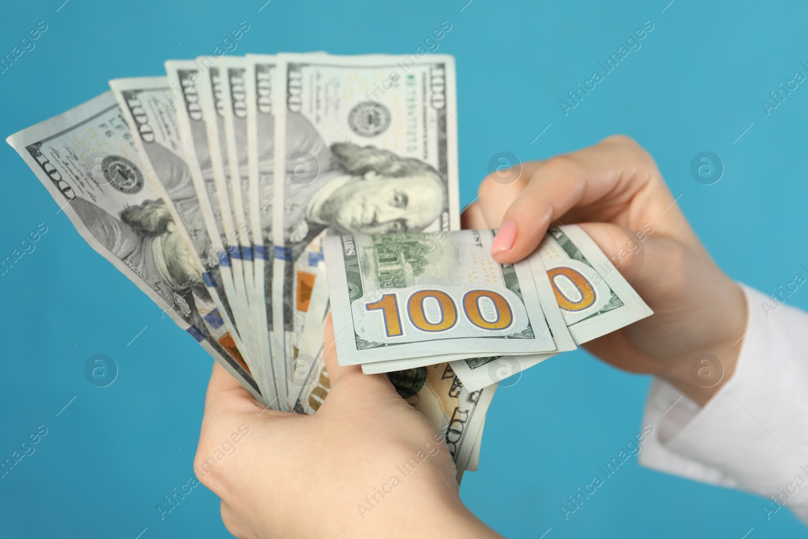 Photo of Woman counting dollar banknotes on turquoise background, closeup. Money exchange concept