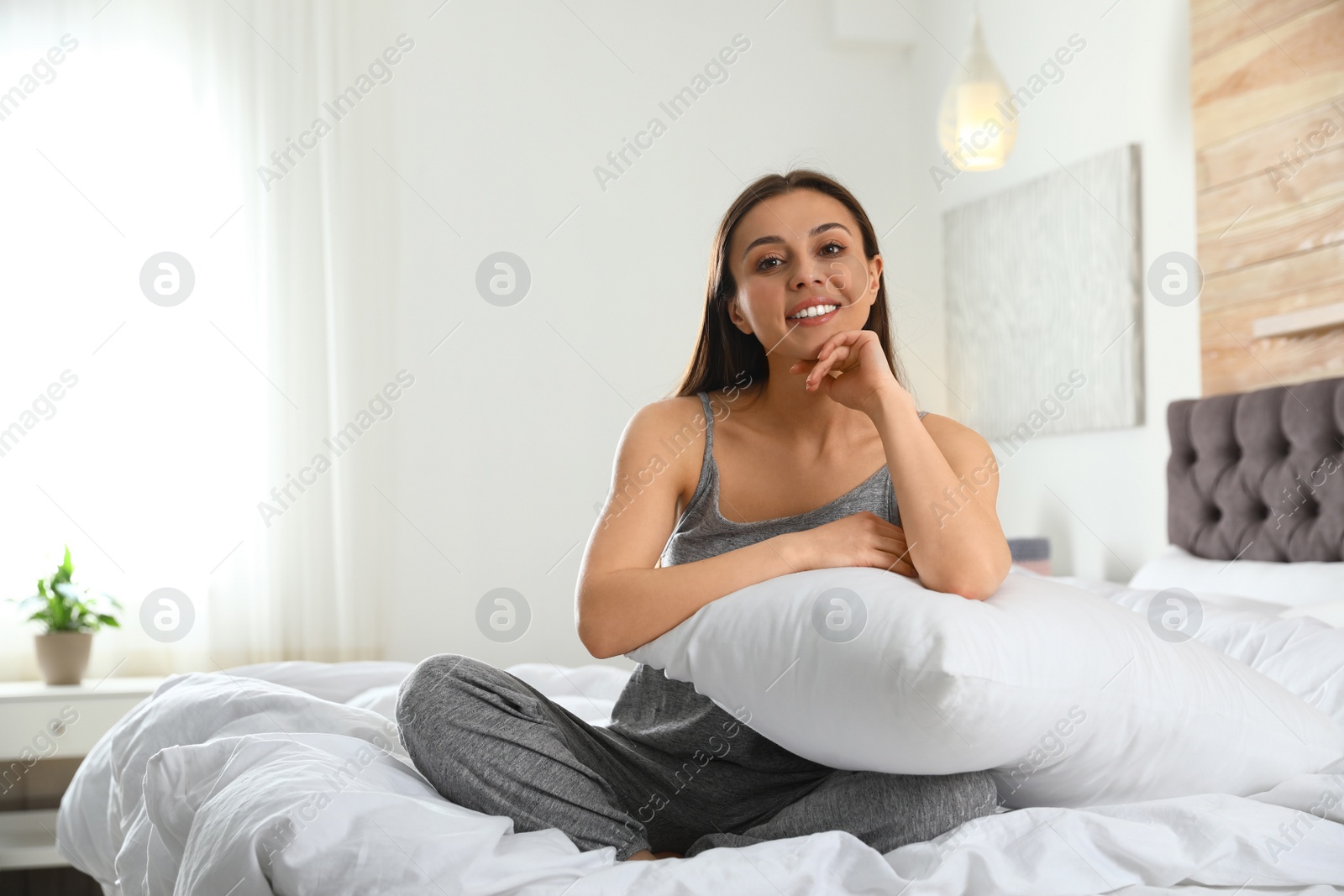 Photo of Portrait of beautiful young woman sitting on large bed