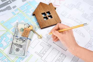 Photo of Cartographer with key, house model and money drawing cadastral map, closeup