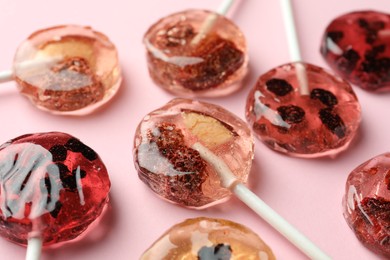 Photo of Sweet colorful lollipops with berries on pink background, closeup