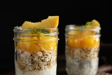 Photo of Tasty peach dessert with yogurt, chia seeds and granola on black background, closeup. Space for text