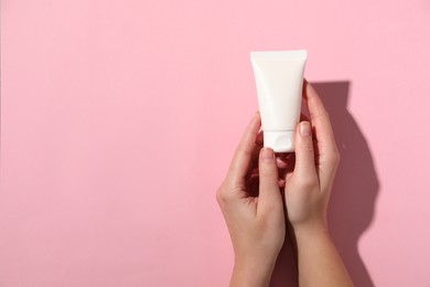 Photo of Woman with tube of hand cream on pink background, top view. Space for text