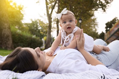 Photo of Happy mother with adorable baby lying in park