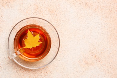 Photo of Cup of tasty tea and autumn yellow leaf on color background, top view. Space for text