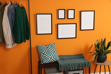 Empty frames hanging on orange wall in stylish room. Mockup for design