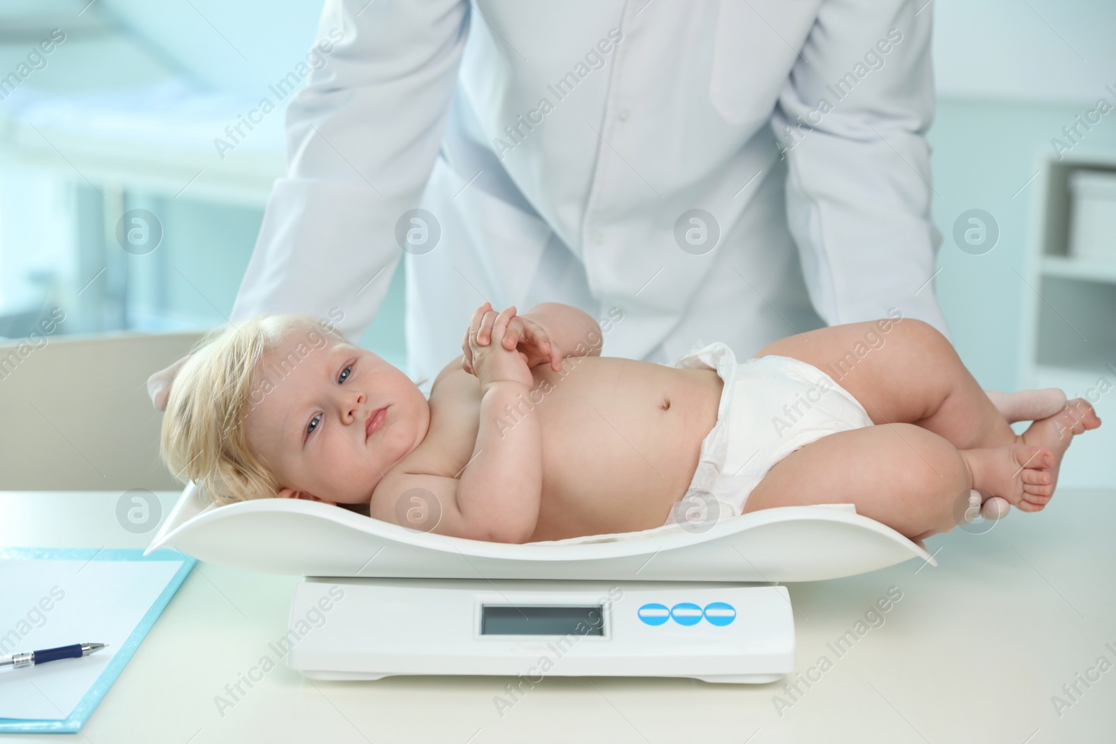 Photo of Pediatrician weighting baby on scale in hospital. Healthy growth