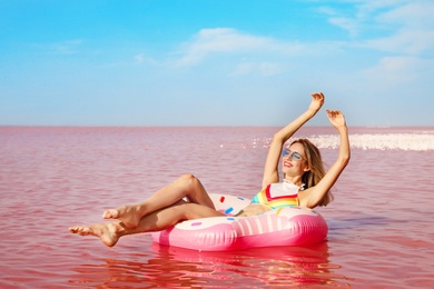 Photo of Beautiful woman on inflatable ring in pink lake