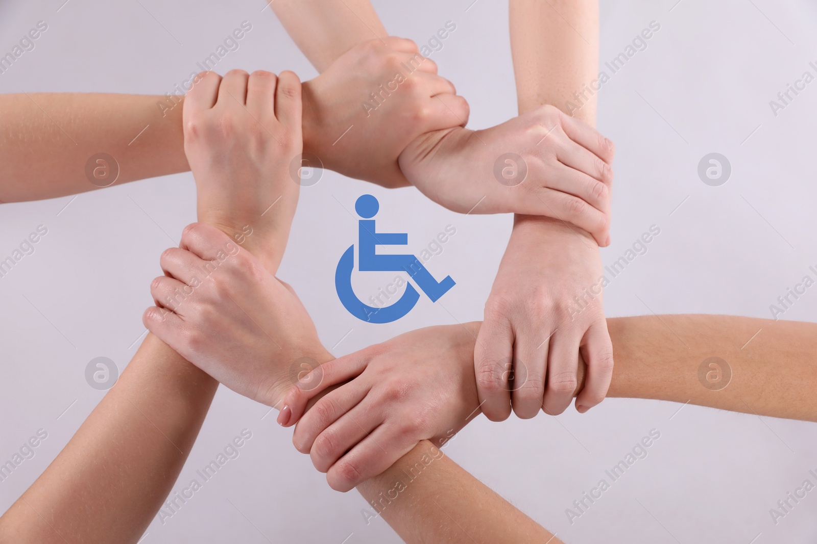 Image of Inclusion concept. People holding hands together around international symbol of access together on white background, top view