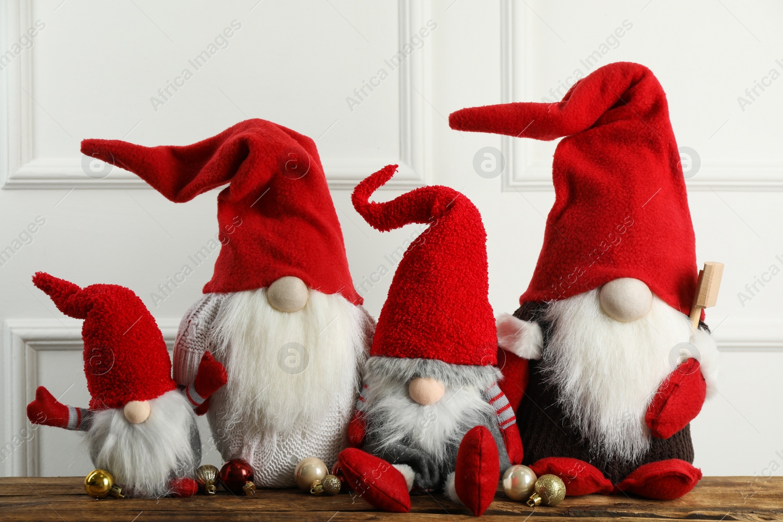 Photo of Many cute Christmas gnomes and festive balls on wooden table