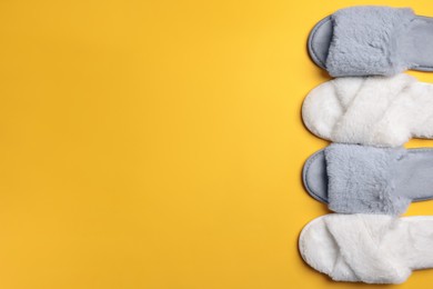 Photo of Different soft fluffy slippers on yellow background, flat lay. Space for text