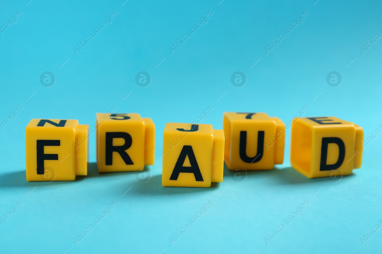 Photo of Word Fraud of yellow cubes with letters on light blue background