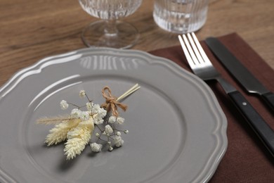 Photo of Elegant festive setting with floral decor on wooden table, closeup