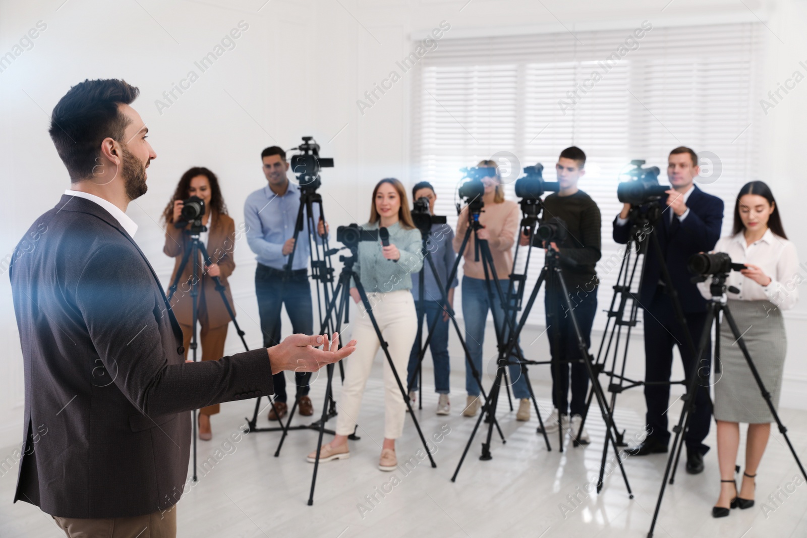 Photo of Happy business man talking to group of journalists indoors