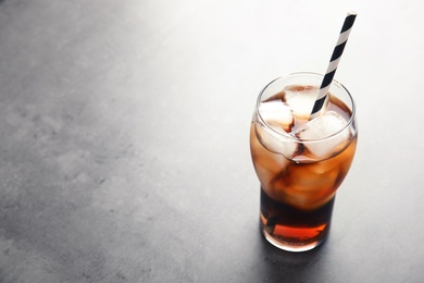 Glass of refreshing cola with ice on grey background. Space for text