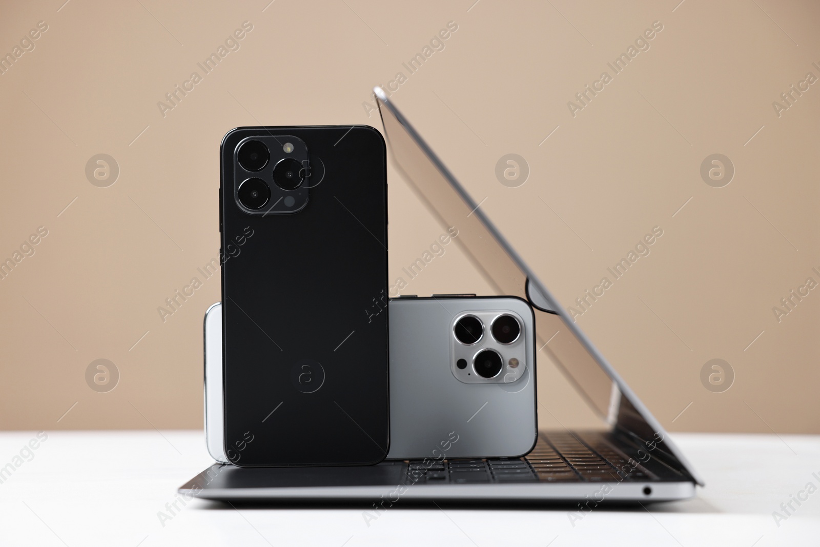 Photo of Modern laptop and smartphones on beige background