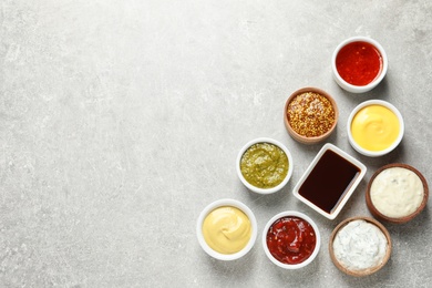 Set of different delicious sauces on grey table, top view. Space for text