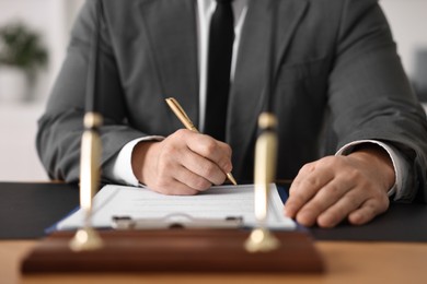 Notary writing notes at wooden table in office, closeup