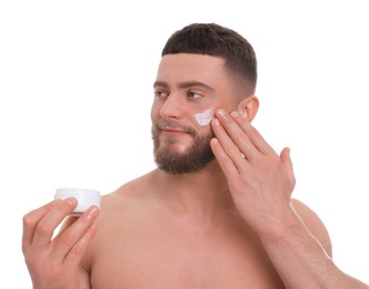 Handsome man applying cream onto his face on white background