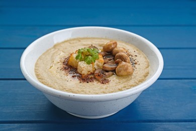 Photo of Delicious cream soup with mushrooms and croutons on blue wooden table