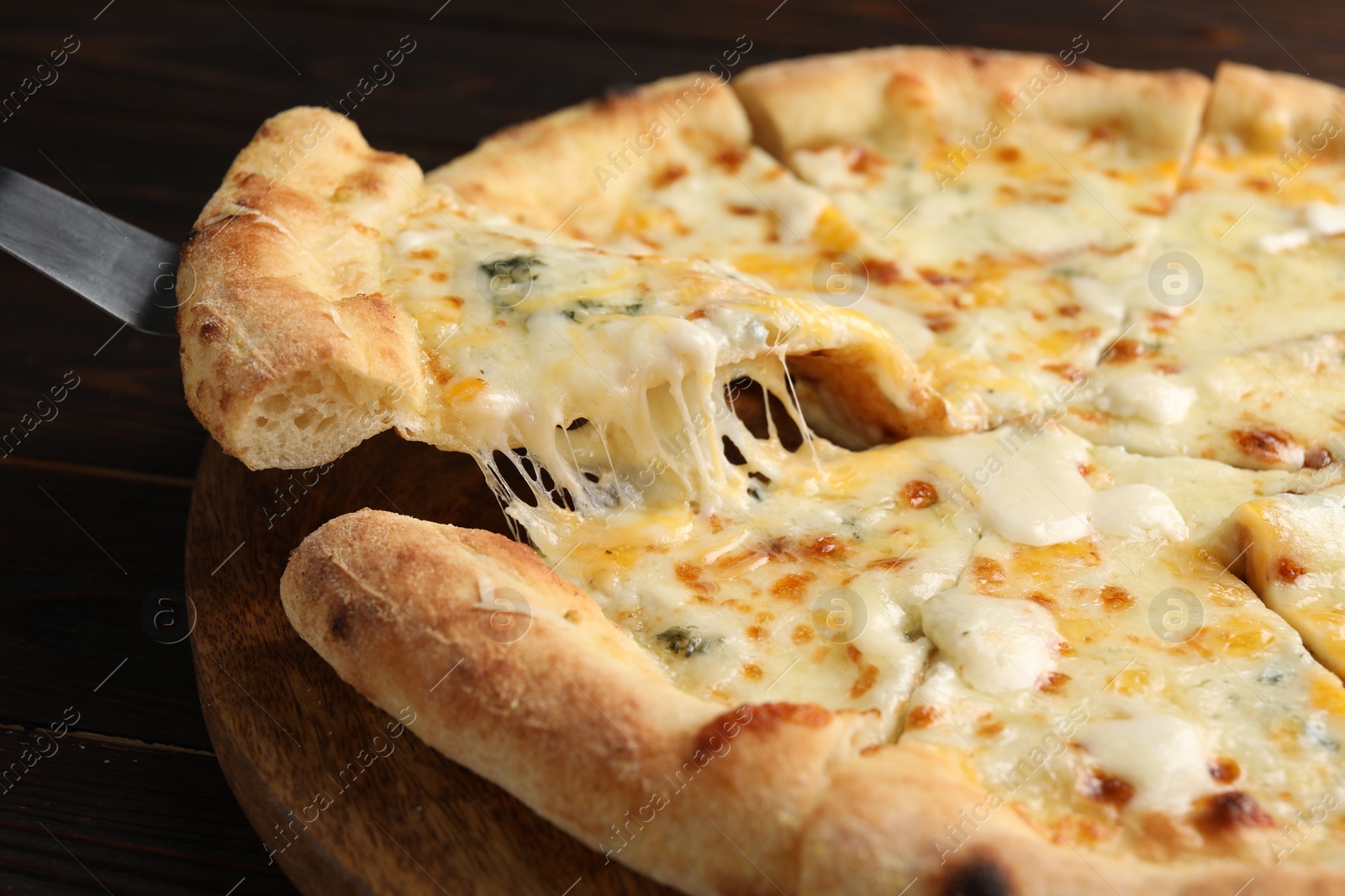 Photo of Taking piece of delicious cheese pizza at wooden table, closeup