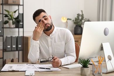 Photo of Overwhelmed man with glasses sitting at table in office