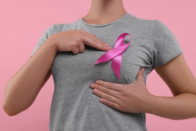 Photo of Woman with pink ribbon on color background, closeup. Breast cancer awareness