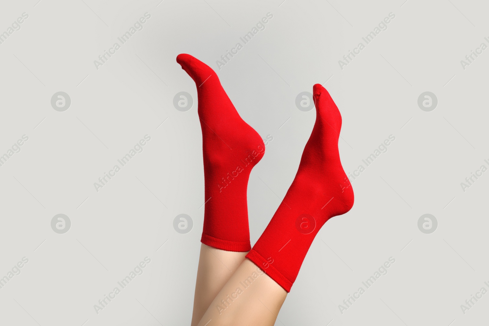 Photo of Woman in stylish red socks on light grey background, closeup