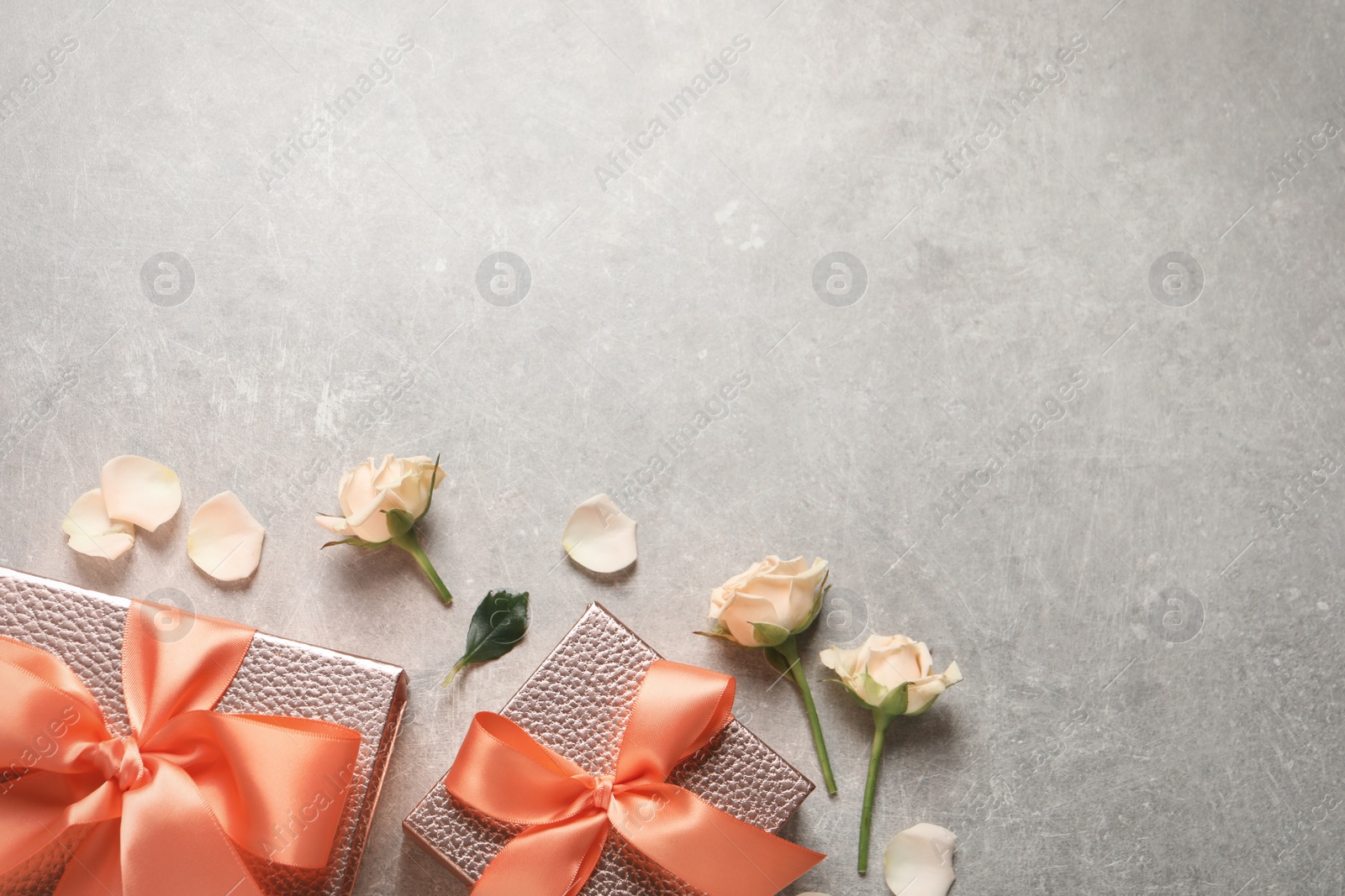 Photo of Pink gift boxes and beautiful roses on grey background, flat lay. Space for text