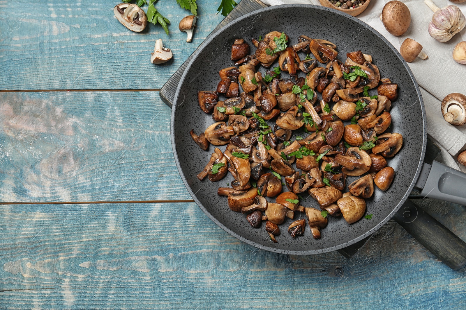 Photo of Frying pan of mushrooms on wooden background, top view with space for text