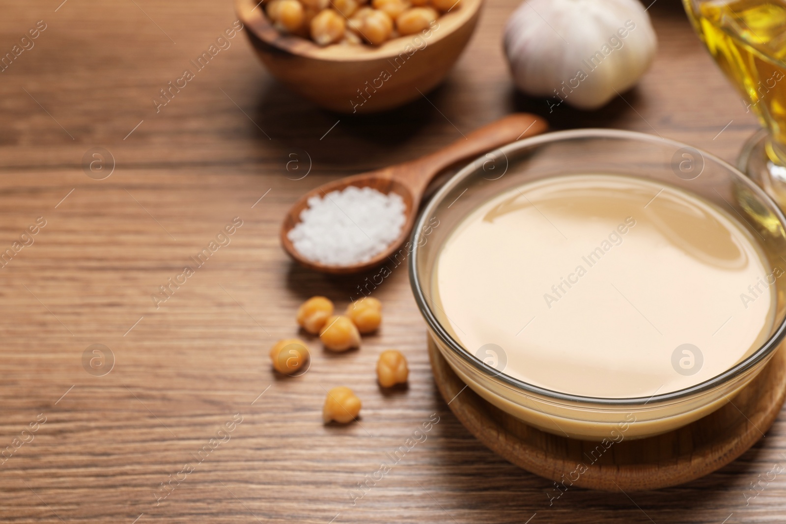 Photo of Different ingredients on wooden table, space for text. Cooking delicious hummus