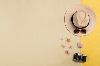 Beach towel, hat, sunglasses, camera, starfishes and sea shells on sand, flat lay. Space for text