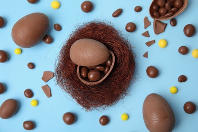 Photo of Flat lay composition with delicious chocolate Easter eggs on light blue background