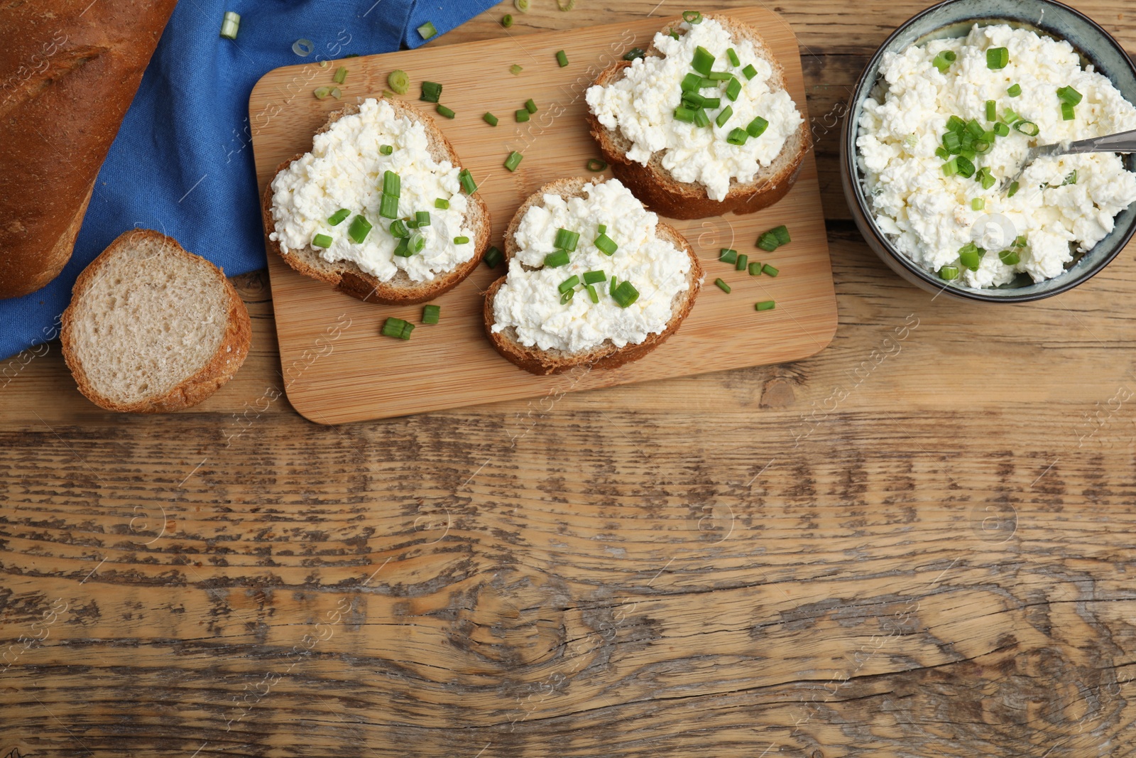 Photo of Bread with cottage cheese and green onion on wooden table, flat lay. Space for text