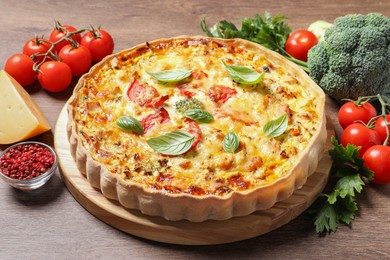 Photo of Tasty cheese quiche and ingredients on wooden table