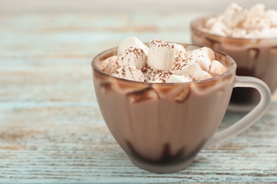 Photo of Cup of chocolate milk with marshmallows on light wooden table, closeup