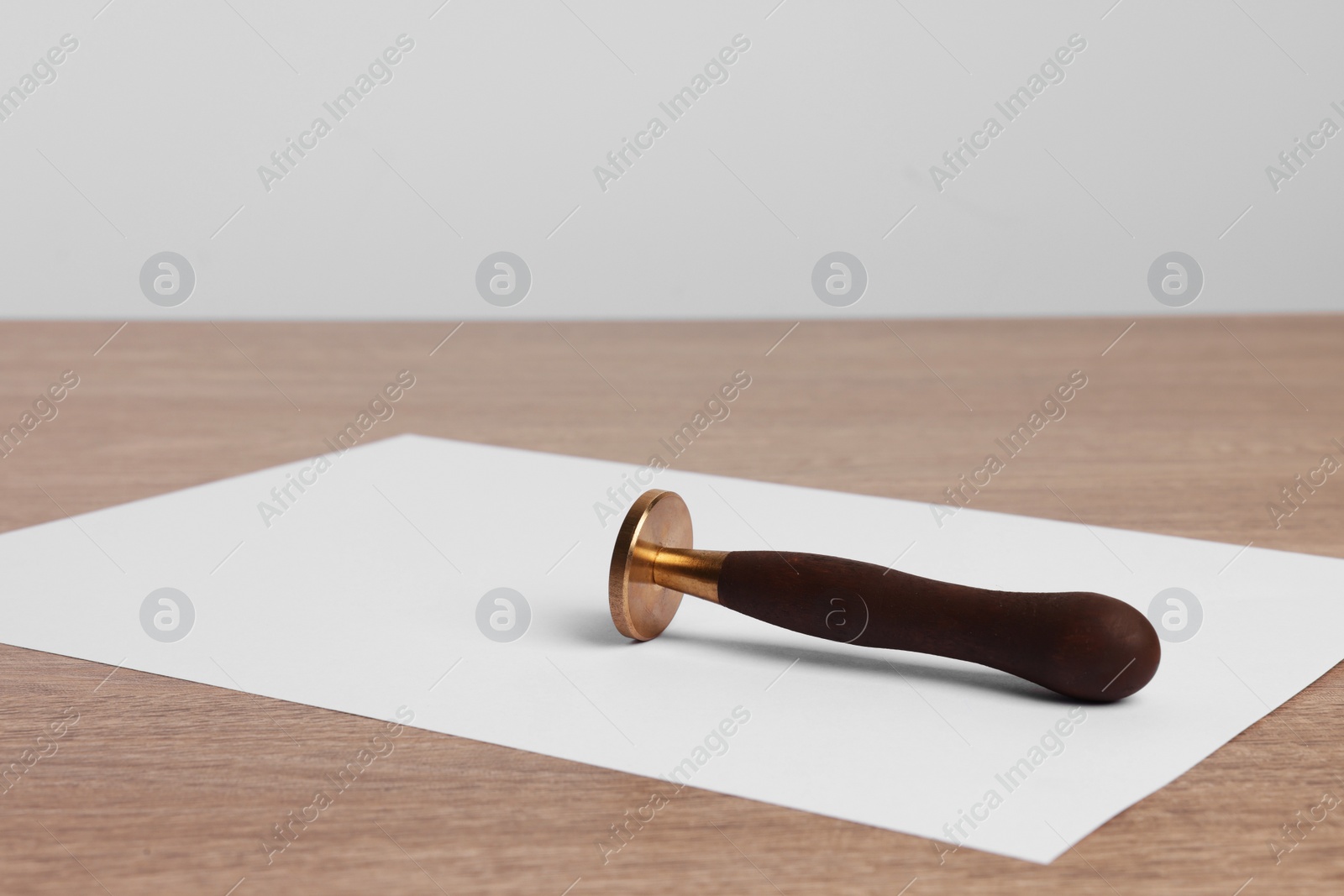 Photo of One stamp tool and sheet of paper on wooden table