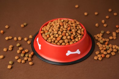 Photo of Dry dog food and feeding bowl on brown background