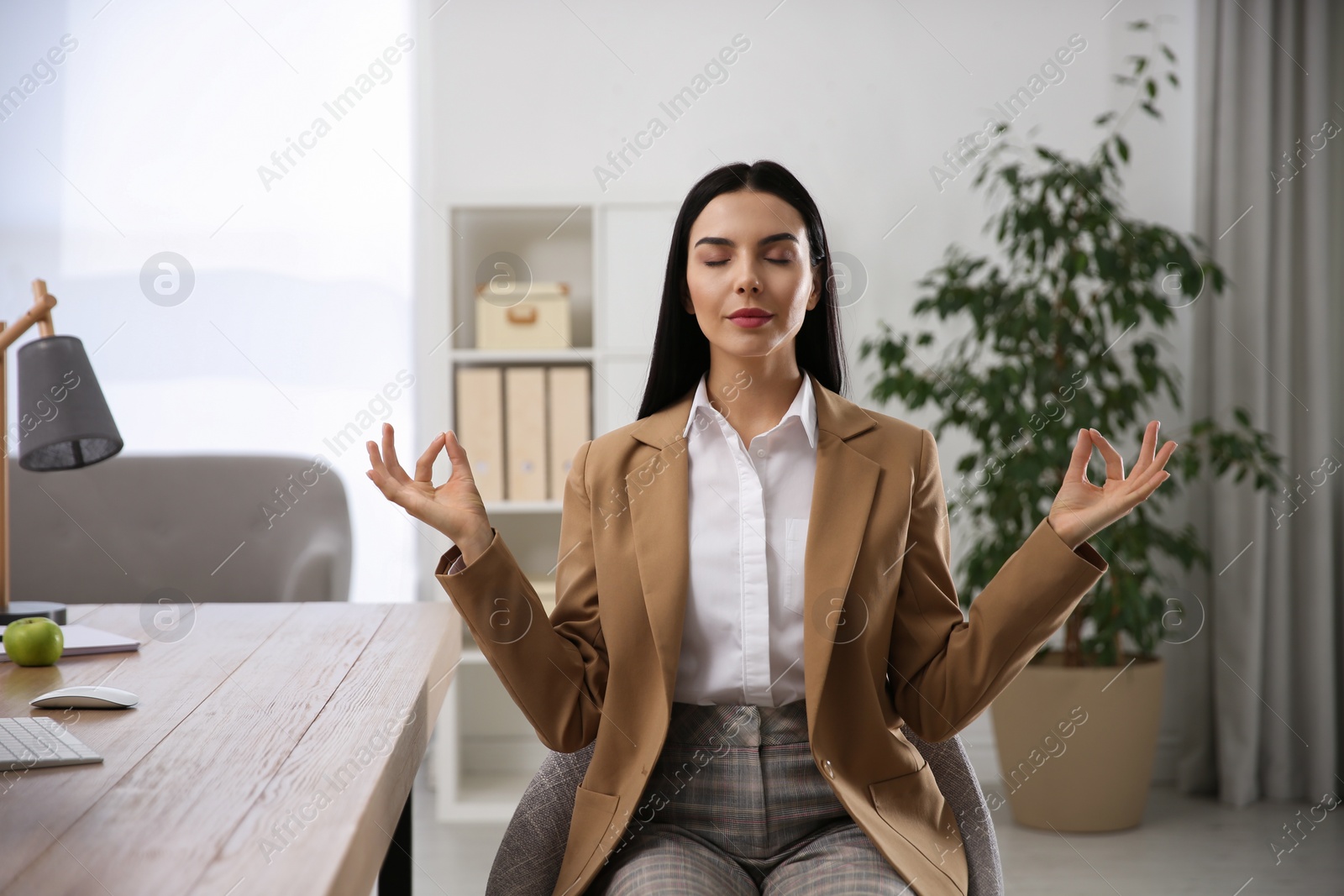 Photo of Young woman meditating at workplace. Stress relief exercise