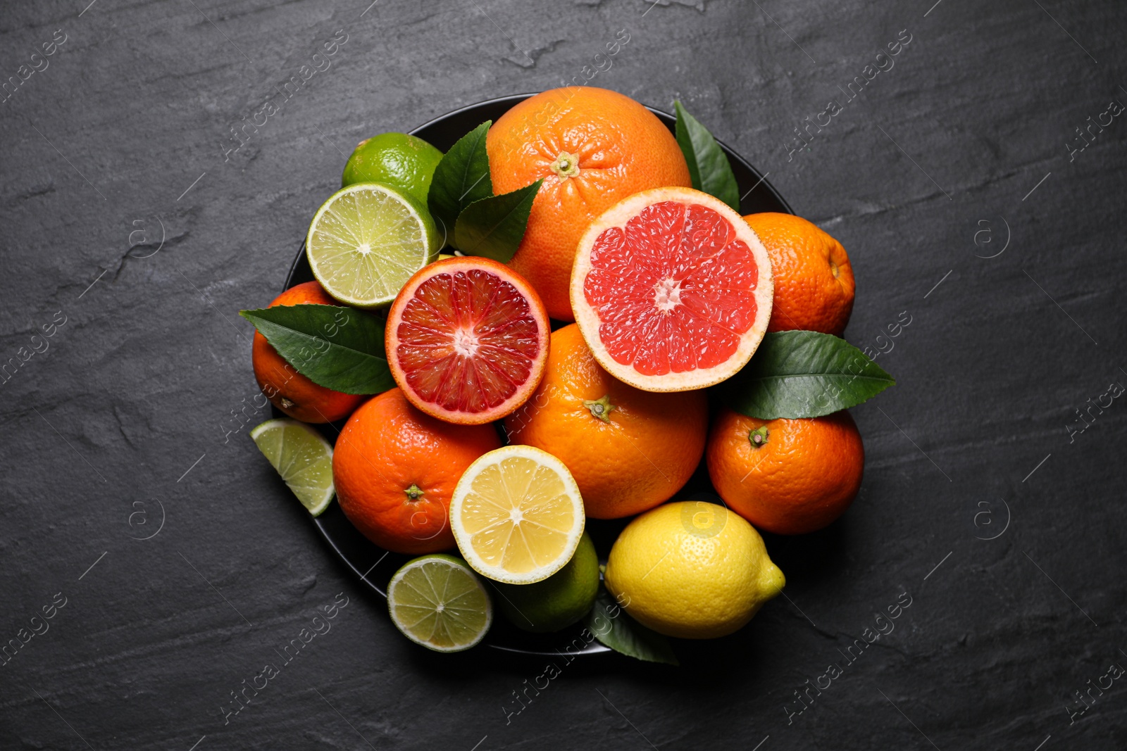 Photo of Different citrus fruits on black table, top view