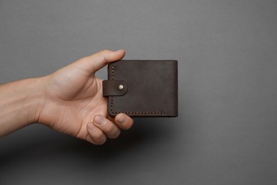 Man holding black leather wallet on dark grey background, closeup. Space for text